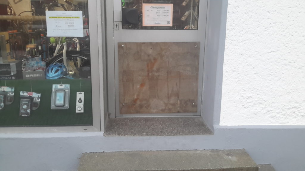 Zerstörte Scheibe in der Tür mit Platte verschlossen